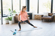 Happy Caucasian female athlete stretching on yoga mat at home indoors. Fit sporty young woman slimming body shaping in the living room indoors