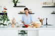 © InsideCreativeHouse - Pretty young woman cooking vegetable salad at home kitchen. Female chef housewife doing lunch dinner, preparing vegan vegetarian meal food indoors