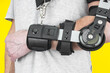 Man close up with a broken arm wearing in adjustable sling on yellow background