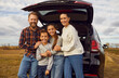 © Studio Romantic - Family of four enjoying road trip on modern automobile. Happy active smiling mum, dad and little kids all together by open car trunk in autumn rural field during roadtrip in countryside.Travel concept