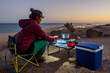 © ADDICTIVE STOCK - Woman enjoys camping and cooking at beachfront site