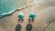 Beach loungers under an umbrella and sea blue water, top view