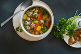 Fototapeta Dinusie - White bean beef meatball soup with  seasonal vegetables on grey background, directly abiove