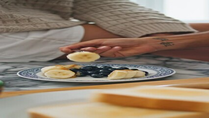 Wall Mural - Closeup hands eating breakfast in kitchen together. Man fingers trying banana