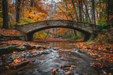 Fototapeta Sport - A bridge over a river with leaves on the ground. The bridge is made of stone and is surrounded by trees. The leaves on the ground are orange and brown, giving the scene a warm and peaceful atmosphere