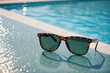 Close up of Sunglasses left at edge of outdoor swimming pool in summer