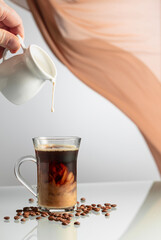 Wall Mural - A man's hand pours cream into a glass of coffee.