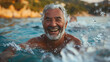 Old man with gray hair, grandpa, swimming and splashing in the sea, water, joyful smiling face, happy and fun on vacation or emigrated to tropical climate.