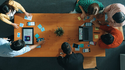 Programmer sharing Ux Ui design for mobile phone interface idea with software developer at meeting while designer writing idea at sticky notes. Start up team develop wireframe prototype. Convocation.