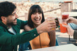 Young Friends Toasting on Beachfront Terrace - A lively group, aged 20-25, celebrates with colorful fizzy drinks, radiating joy on a seaside terrace.
