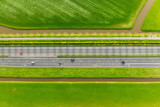 Fototapeta  - Drone view of a road in the middle of a field. Landscape from a drone. Road and transport. Car traffic. Rows on the field. View from above.