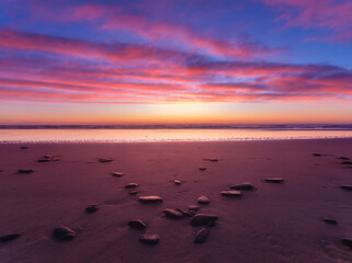 Canvas Print - Seascape during sunrise. Bright clouds on the sky. Lines of sand on the seashore. Bright sky during sunset. A sandy beach at low tide. Wallpaper and background.