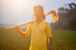 young farmer holding a grub hoe on his shoulder standing in the field in warm sunset light