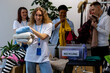 Group of volunteers, young women and man, sorting clothes in charitable foundation for charity donation, recycling. Concept of textile pollution, conscious consumption. Ecology, sustainable lifestyle