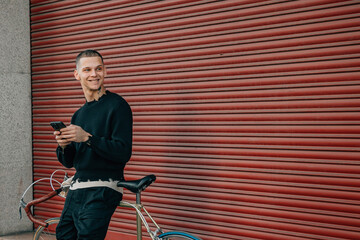 Wall Mural - young man with mobile phone and bicycle on the street in red background