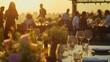 © netrun78 - Close-up of a sunset dining setup outdoors, featuring glasses of wine and plates of gourmet food with people socializing in the background. Birthday, corporate party celebration.