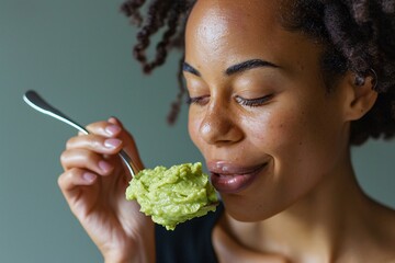 Wall Mural - Detailed close-up of a woman savoring a spoonful of velvety mashed avocado