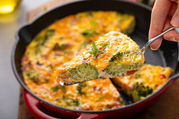 Wall Mural - Healthy frittata or quiche with broccoli and red pepper cooked in a cast iron pan