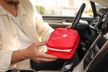 Wall Mural - Man with first aid kit inside car, closeup