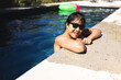 © Wavebreak Media - A teenage Asian boy relaxing in the pool outside at home, wearing sunglasses, copy space