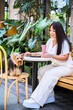 Cheerful woman has breakfast with her adorable yorkie at a sunny outdoor cafe