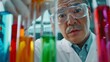 © Justlight - A scientist in a white lab coat and goggles carefully holding up a test tube filled with a multicolored liquid. The colorful mixture fills the frame highlighting the various chemicals .