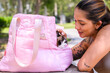 Smiling woman interacts with her kitten peeking from a pink tote bag outdoors