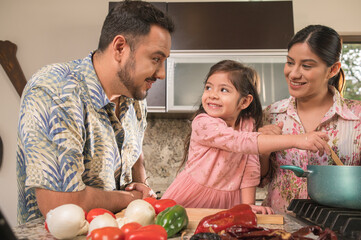 Hispanic family happily cooking. Modern and young couple cooking together at home.
