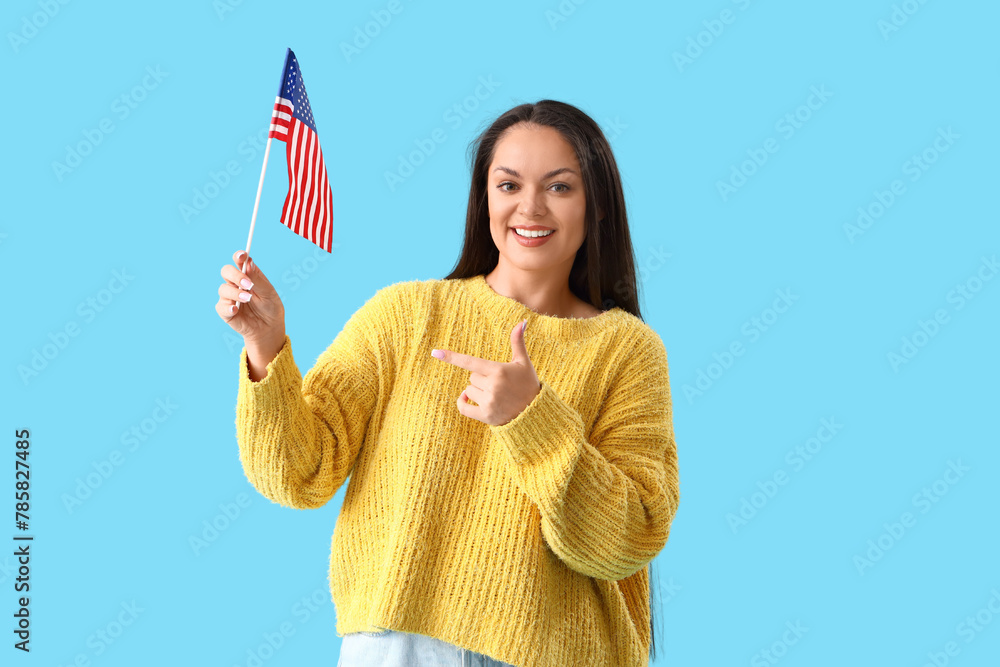 Young woman pointing at USA flag on blue background