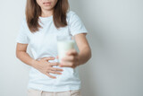 Fototapeta Kwiaty - Lactose intolerance and Milk allergy concept. woman hold Milk glass and having abdominal cramps and pain when drink Cow Milk. Symptom stomach ache, Dairy intolerant, Nausea, Bloating, Gas and Diarrhea