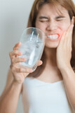 Fototapeta Kwiaty - Teeth Sensitive to Cold concept. woman hold Ice Water glass and having toothache and pain after eat. Tooth Decay or Gum Disease, Grinding Teeth and Stress, Exposed Nerve Roots, Crack and Receding Gums