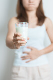 Fototapeta Kwiaty - Lactose intolerance and Milk allergy concept. woman hold Milk glass and having abdominal cramps and pain when drink Cow Milk. Symptom stomach ache, Dairy intolerant, Nausea, Bloating, Gas and Diarrhea