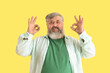 © Pixel-Shot - Mature bearded man showing OK on yellow background