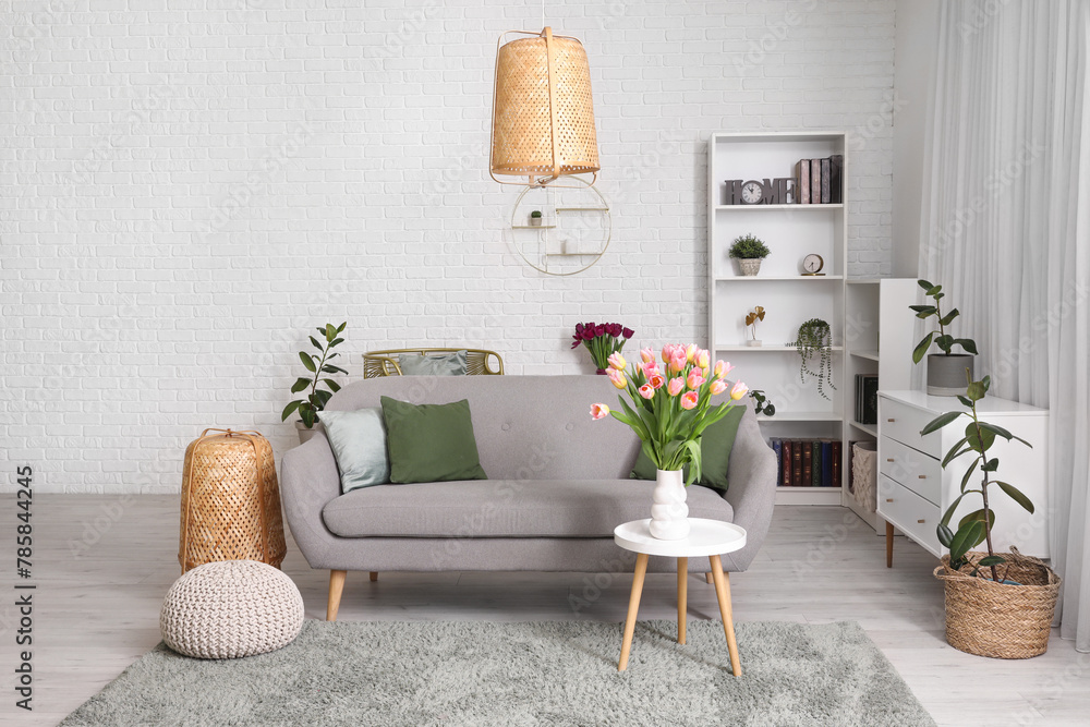 Interior of modern living room with comfortable sofa, table and flowers