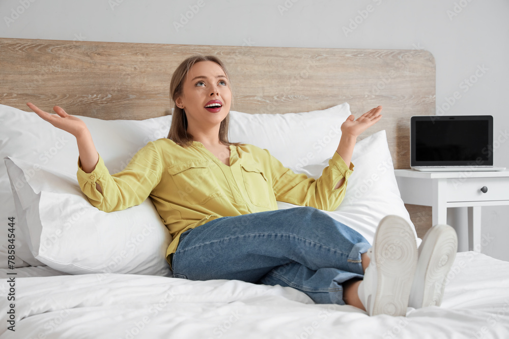 Happy young woman lying on comfortable bed in bedroom