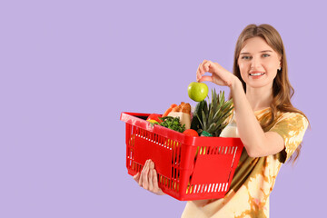 Poster - Young woman with full shopping basket on lilac background