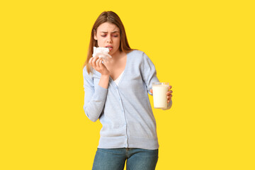 Poster - Young woman with glass of milk and tissue suffering from allergy on yellow background