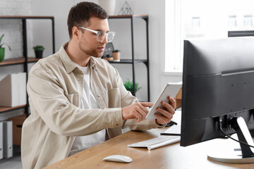 Portrait of focused male programmer working with tablet computer in office