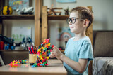 Fototapeta  - A child boy in the children's room is playing with a toy constructor for teaching the science of chemistry. Assembling molecules from elements. Children's scientific education