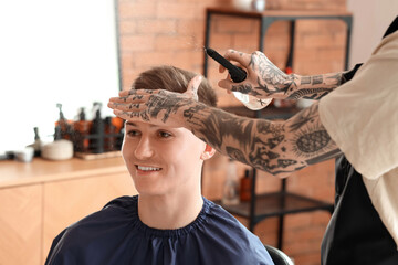 Wall Mural - Male hairdresser spraying client's hair in barbershop, closeup