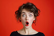 A surprised woman with her mouth open in disbelief on a red background