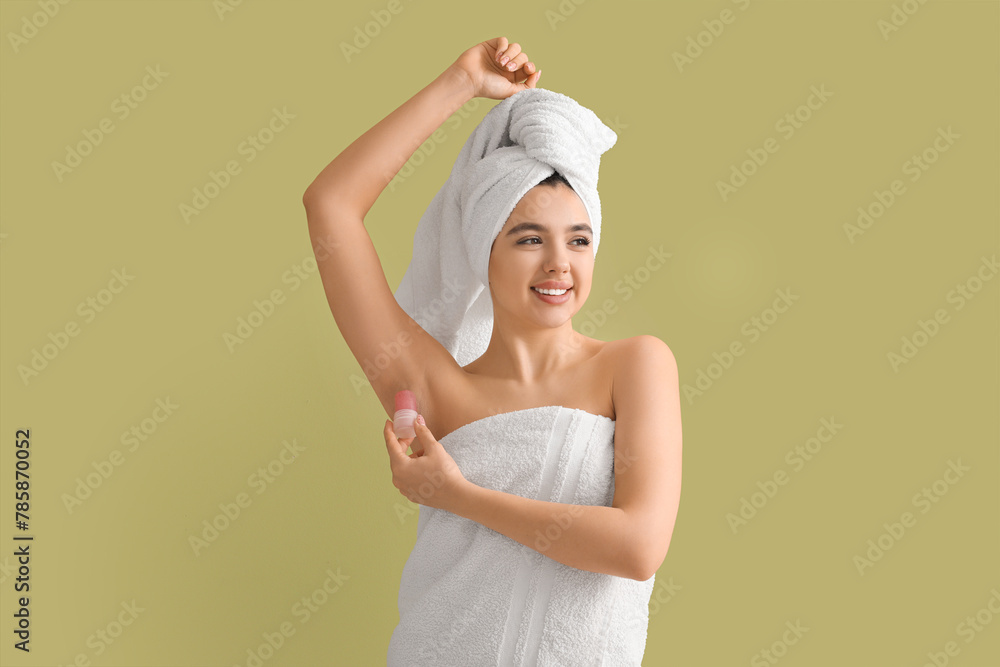 Happy smiling young woman in towel using crystal deodorant on green background