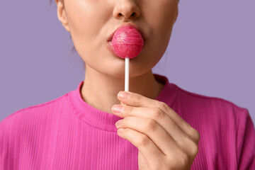 Canvas Print - Young woman with sweet lollipop on lilac background, closeup