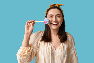 Poster - Happy young woman with sweet lollipop on blue background