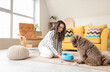 Young woman feeding cute poodle at home