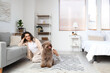 Young woman with cute poodle sitting on floor at home
