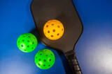Fototapeta Dziecięca - Paddle and pickleball ball in blue background. Pickleball is a new sport that is developing and starting to be popular with the public.