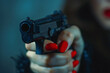 Close up of woman's hand with red painted fingernails holding gun