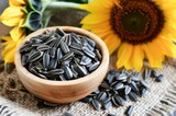 Fototapeta Lawenda - Sunflower Seeds Scattered on a Rustic Table With Sunflowers in Bloom