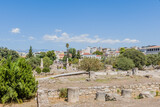 Fototapeta Desenie - Ancient ruins in a field with a modern city and clear blue sky in the background, in Athens, Greece
